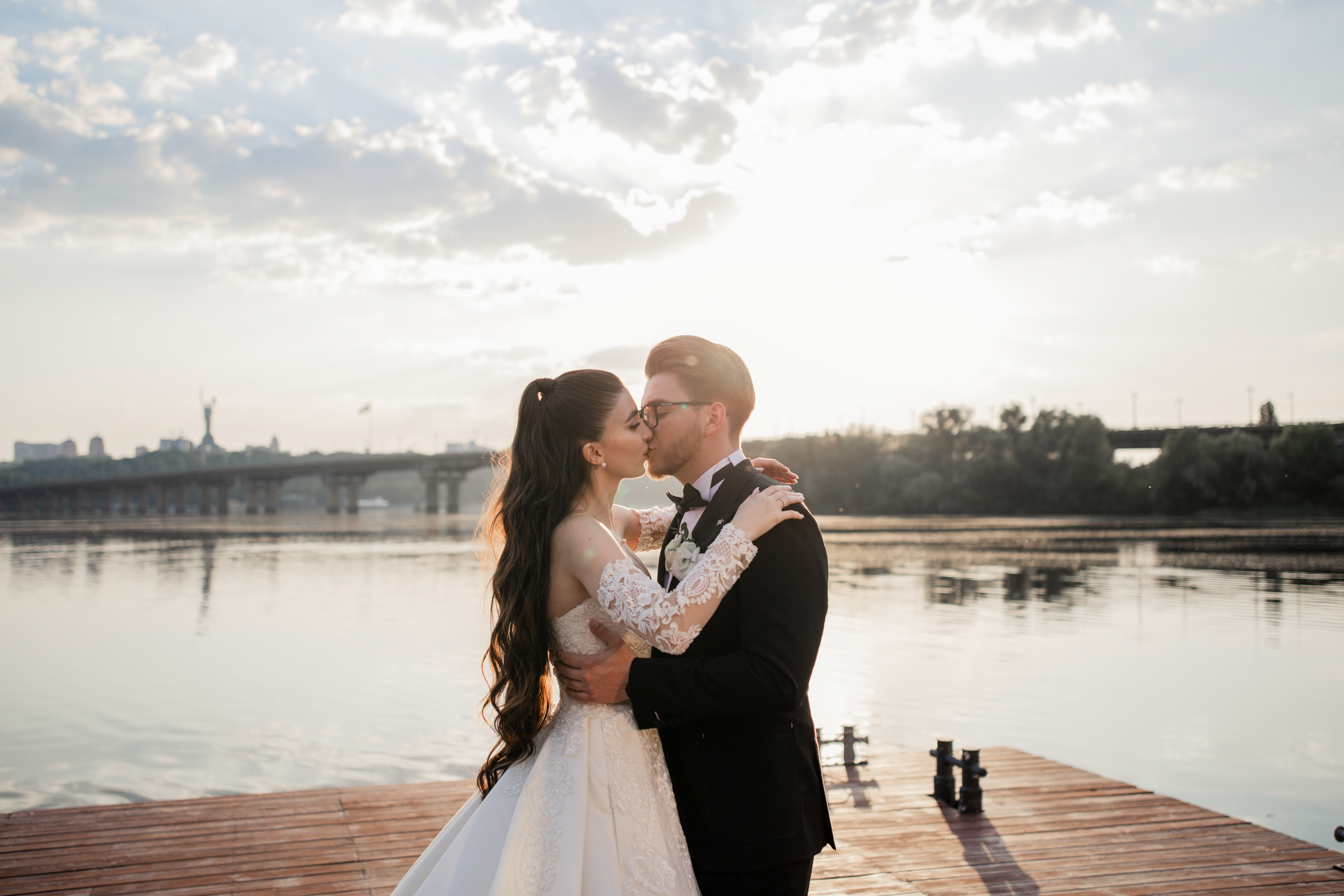 Newlyweds embracing by the water in warm evening light