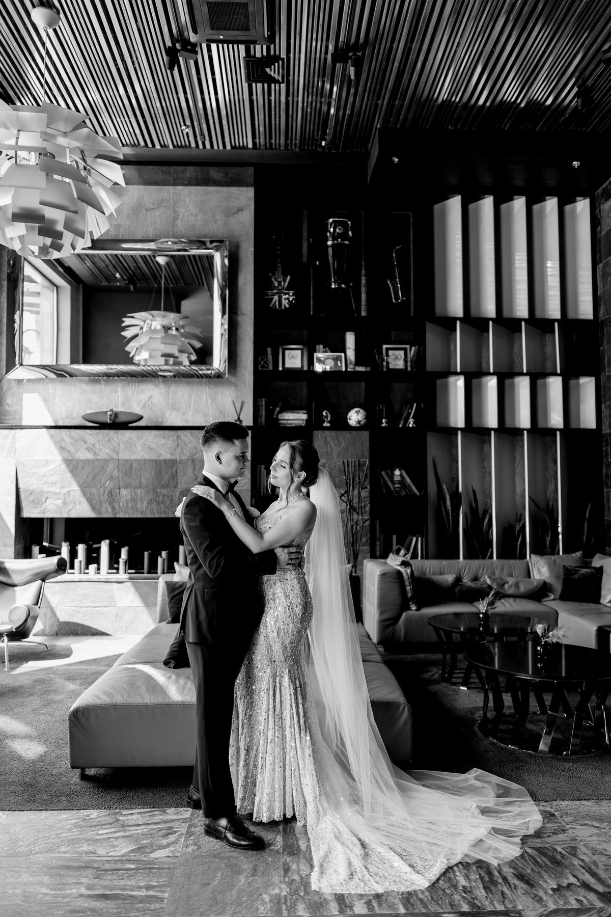 Bride and groom embracing in a dramatic black-and-white interior